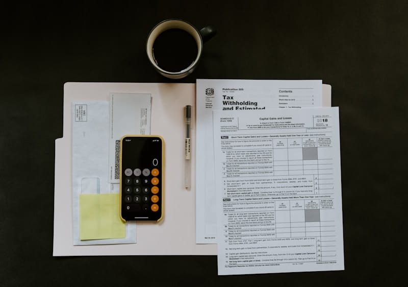 Tax forms, calculator, and coffee on a desk — US expat tax filing from Colombia